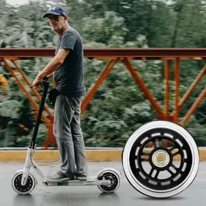Person riding a scooter with a close-up of 100mm scooter replacement wheels pair with ball bearings black pro stunt wheels.