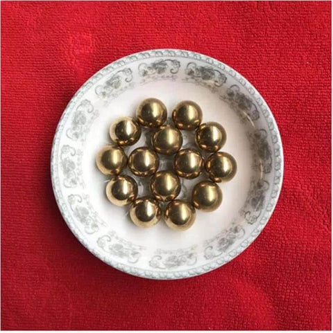 12mm 50pcs Solid Pure Copper Balls - Brass Ball Bead on a decorative plate, used for machinery and artware, on a red background