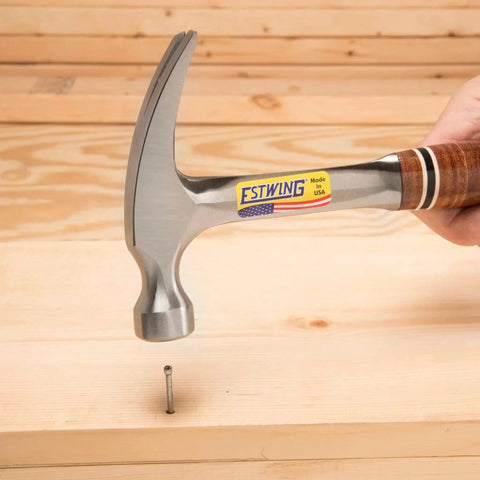12 Oz Straight Rip Claw Hammer With Smooth Face And Genuine Leather Grip For Framing Carpentry Demolition And Woodworking Made In USA From Forged Steel Pro Grade Hand Tool For Precision Strikes And Durable Performance in use driving a nail into wood.