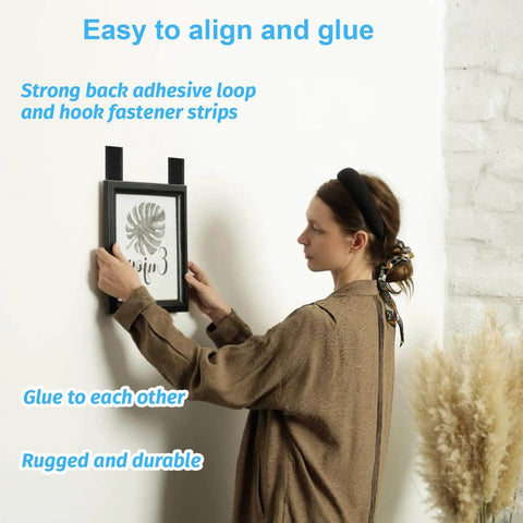 Person using 32 Sets 1x4 Inch Hook And Loop Strips With Adhesive Heavy Duty Mounting Strips For Wall Hanging Pictures on white wall