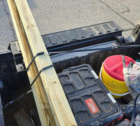 Truck bed loaded with a wooden plank secured by 50 Pack 21 Inch Natural Rubber Tarp Bungee Straps With S Hooks Tie Downs
