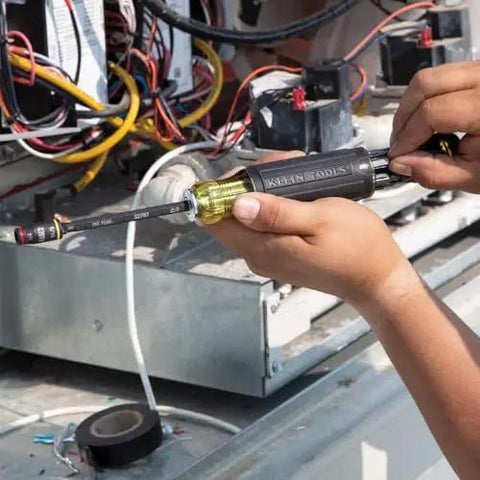 Person using Klein Tools 3-In-1 Flip Impact Socket Set for Quick Drive Size Swaps on electrical machinery.
