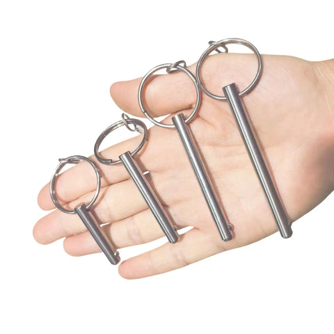 Hand holding four sets quarter inch diameter single ball quick release pins made from 316 stainless steel with lanyard and screws.