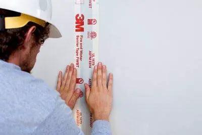Applying Fire and Water Barrier Tape FWBT4 4 in x 75 ft 1 roll self-adhesive elastomeric firestop seal on wall joint