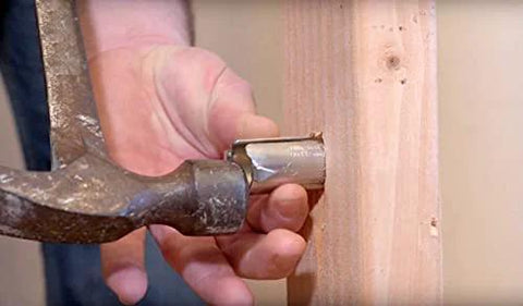 Southwire Smart Shield wire protection guard mounted on a wooden stud, hammer poised to secure the nail guard