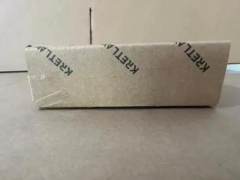 Side view of a cardboard box with 'KREML' branding, potentially containing Mini Grease Gun Kit 3000 PSI With Double 3oz Cartridges And 12 Inch Flex Hose Pro Grade Reinforced Coupler For Automotive And Marine Use Includes Extension Pipe 4 Jaw Coupler Sharp Nozzle Extension Adapter And Gloves.