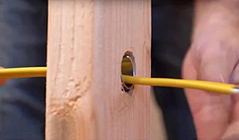 Southwire Smart Shield wire protection guard for studs; yellow electrical cable through a drilled wood stud hole