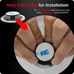 Close-up of hands applying pressure on the adhesive backing for the Blind Spot Mirror Set For Cars 2 Inch Round HD Glass Frameless Convex Rear View Mirrors Pack Of 2 Ampper.