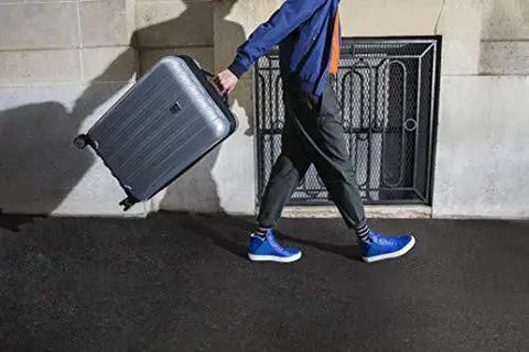 Person rolling Lightweight Expandable Hardside Luggage With Four Double Spinner Wheels And A Crack Resistant Polycarbonate Shell in urban setting.