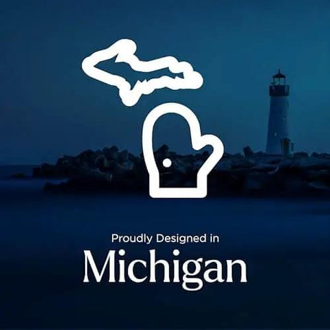 Silhouette of Michigan map and mitten against lighthouse and water, text 'Proudly Designed in Michigan.'