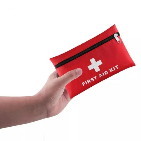 Hand holding red pouch of Grab-And-Go Compact Travel First Aid Kit With 95 Piece Emergency Set For Carry-On Backpacking And Road Trips