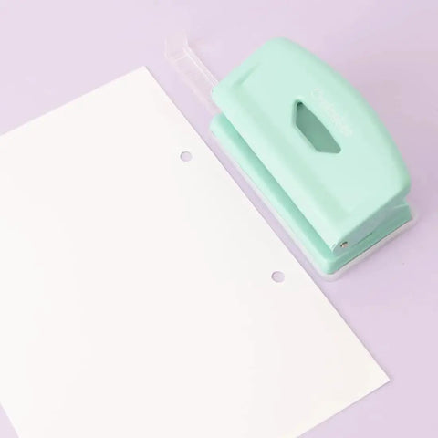 Mint finish 2 Hole Puncher With Waste Tray, 10 Sheet Capacity, by a sheet with punched holes, highlighting adjustable guide and non-slip base.