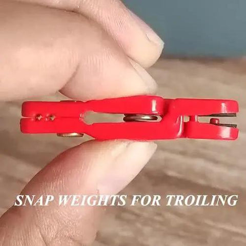 Close-up of Eight Pack Heavy Tension Snap Weight Trolling Release Clip held between fingers, ideal for planer boards, corrosion-resistant.