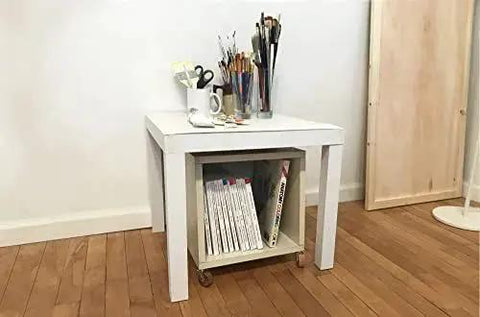 White side table with magazines and brushes on top, visible brown wheel stem casters underneath for mobility and style.