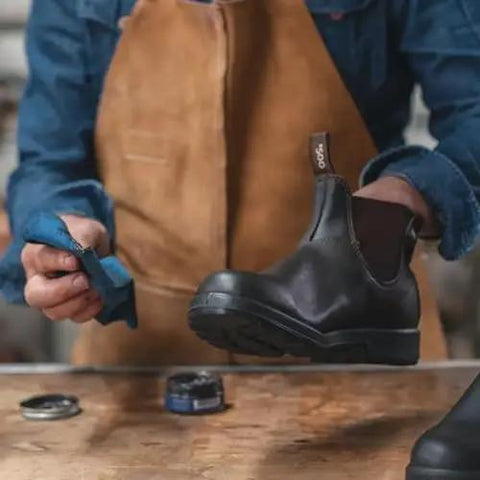 Person applying Leather Care Renovating Cream For Rustic Leather To Nourish And Condition Boots And Shoes From Blundstone on a black boot.