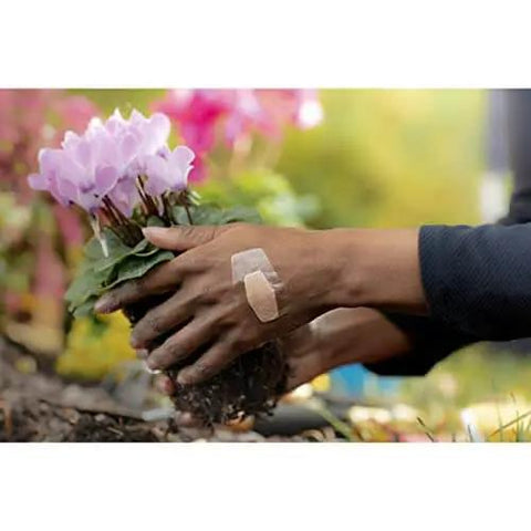 Person gardening with waterproof clear bandage on hand, demonstrating Waterproof Clear Bandages Assorted Sizes 100 Count With 360 Degree Seal.