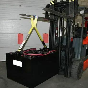 Industrial forklift battery lifting sling, front view, yellow straps lifting a large black battery beside a forklift.