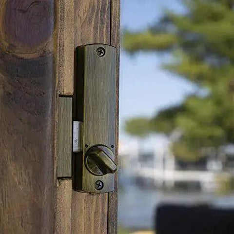 Close-up of Keyless Surface Mount Hook-Bolt Lock For Sliding Doors In Antique Brass installed on wooden sliding door.