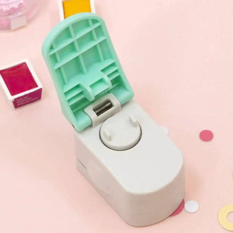 Circle Punch With Reinforcing Ring And Snap Lever For Paper Crafting on a table with scattered paper cut-outs