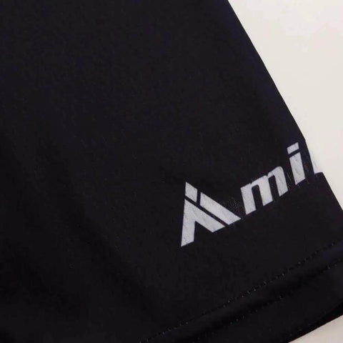 Close-up view of black fabric material with partial visible logo design on garment edge, showcasing texture and stitching.