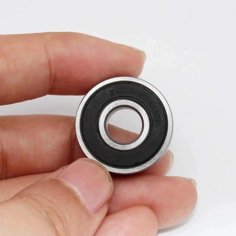 Close-up of 6082RS Ball Bearings with double rubber seal, ideal for skateboards and roller blades, held between fingers, showcasing size 8x22x7mm.