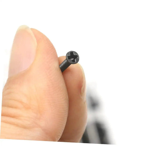 Close-up of a screw from the Miniature Screw Assortment Kit With 18 Sizes In Transparent Storage Case held between fingers.