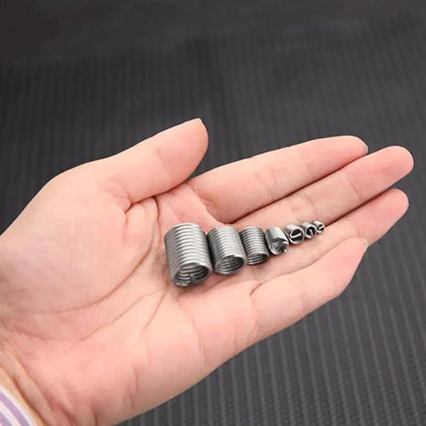 Hand holding various sizes of 304 stainless steel helical wire inserts, part of a Thread Repair Kit With 140 Pcs 304 Stainless Steel Helical Wire Inserts M3 To M12 In 7 Sizes, Coiled Helicoil Type Screw Sleeve Set In A 10 Compartment Storage Box Included, Durable Metal Sleeve Repair Kit For Damaged Threads.