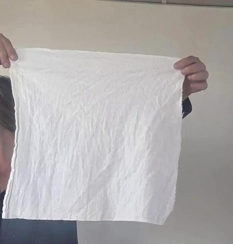 Person holding a Medical Grade White Cleaning Rag Lint Free Industrial Shop Towel for Mechanics and Painting.