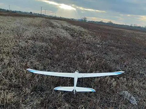 White RC plane with blue accents flying over a field, powered by Dope 4 Pack Micro Servo Motors 9G Geared RC Servos For DIY Robots And RC Projects.