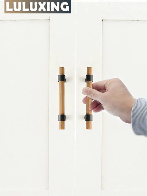 Hand holding Six Pack Solid Wood Cabinet Handles And Pulls 4.4 Inch Center To Center on white doors.