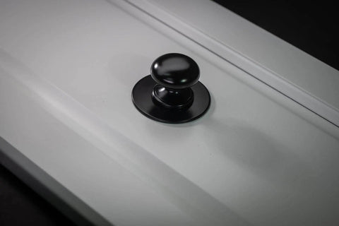Matte Black Escutcheon Back Plates For Cabinet Knobs And Doors Four Pack Round Rosette Plate Two And One Third Inch Heavy Duty Die Cast Zinc Ideal For Bifold Closet Doors Door Pulls And Handles installed on a white cabinet door.