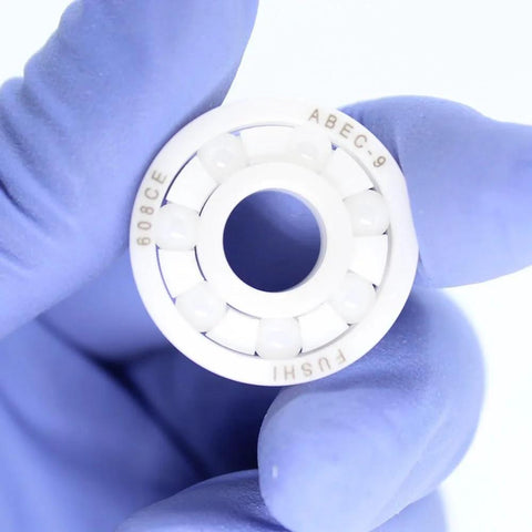 608 ZrO2 full ceramic ball bearing with white outer race and ceramic balls, held by gloved hand.