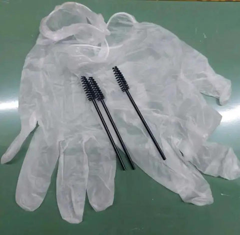 Disposable gloves and mascara brushes on a green surface