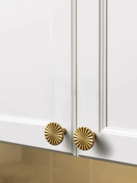 Antique Brass Cabinet Knobs 10 Pack Vintage Flat Drawer Pulls installed on white kitchen cupboard doors.
