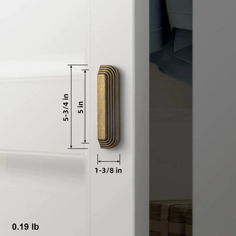 Side view of installed 5-inch antique brass cup pull with distinctive layered ribbed multi-sectioned design on white cabinet.