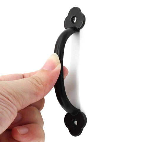 Close-up of a hand holding a black metal handle from the 12 Pack Rustic Barn Door Handles Set 4 Inch Length Hole To Hole 3.2 Inches.