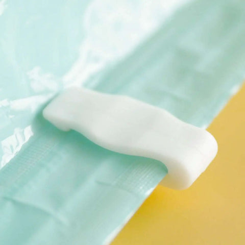 Close-up of white sealing clip on vacuum storage bag, part of Ten Pack Vacuum Storage Bags Sealing Clips Set With Reusable Zipper Grips