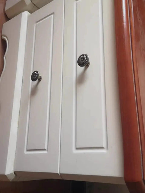 Close-up of vintage flower shape cabinet knobs set of 6 bronze tone metal drawer pull handles with screws installed on white cabinet