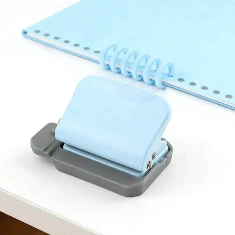 Blue and gray metal Six Hole Spiral Binding Punch for planners and home office, shown with binder rings and 8-sheet capacity paper.