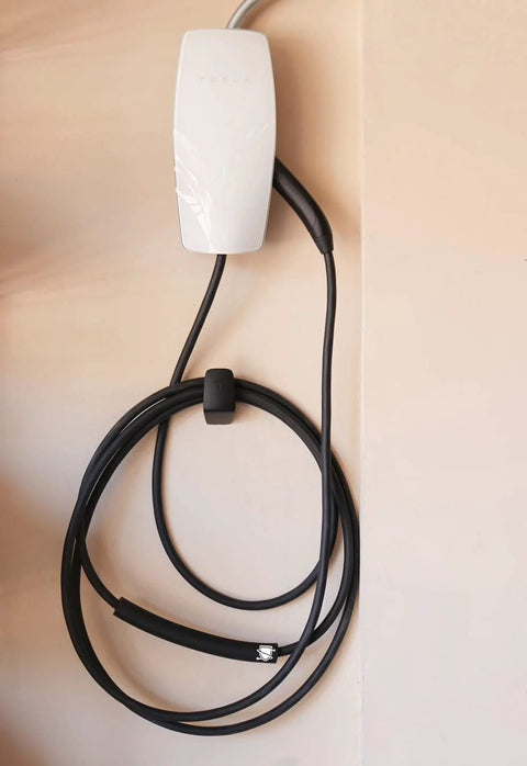 Cable Shield-EV cable protector mounted on wall; white housing with Tesla charging cable coiled below, black cord.