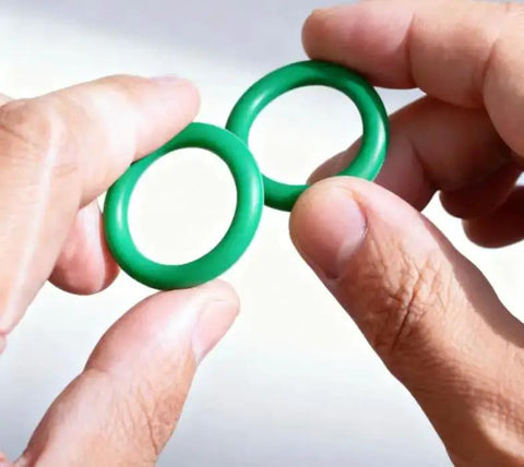Holding two green rubber seals from 270 Pcs Rubber O Ring Kit With 18 Sizes High Temperature Buna N Seals For Industrial Pneumatic AC Plumbing Repairs