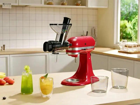 Front view: red KitchenAid stand mixer with black masticating juicer attachment.