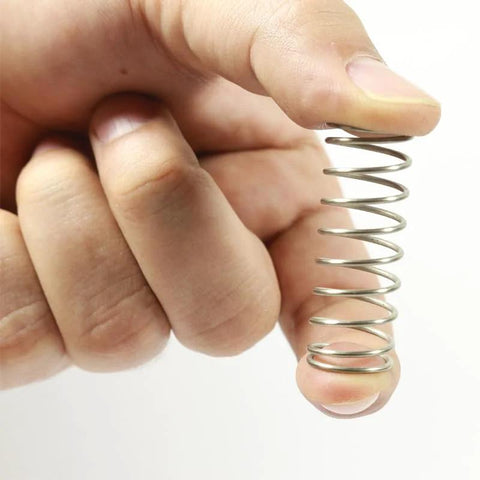 Compression spring, stainless steel, close-up held between fingertips for DIY repair projects
