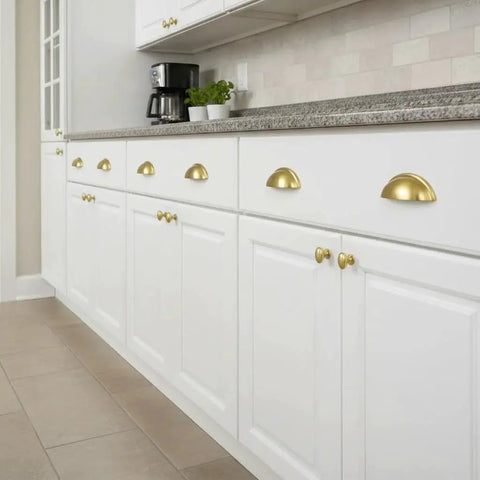 Brushed Gold Cup Drawer Pulls 3 Inch 76mm Set of 10 installed on white kitchen cabinets, showcasing elegant design and durable metal finish.