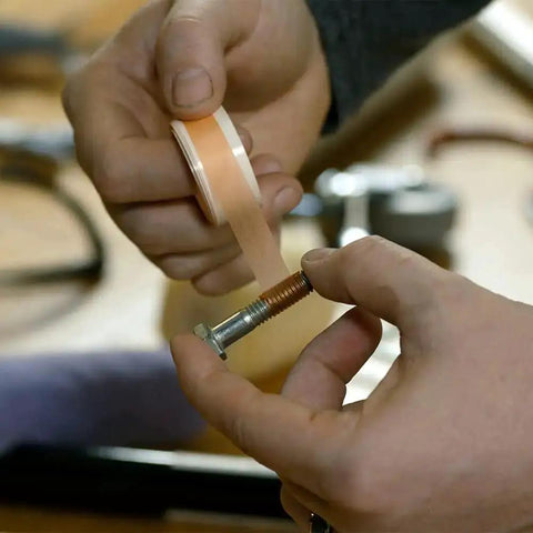 Person using Tank Bond Thread Stopper Tape Orange for interior and exterior loose screws, shown wrapping tape around a bolt.