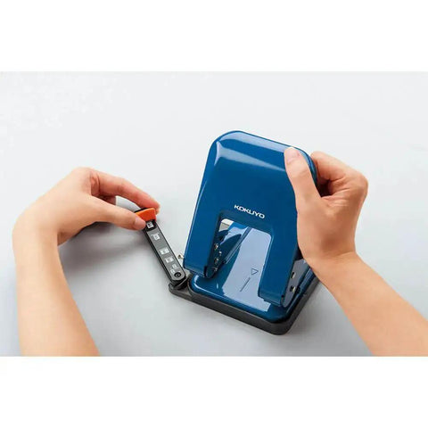 Person adjusting paper guides on Heavy-Duty 2-Hole Punch With Smooth Action, Handles Up To 37 Sheets, blue ergonomic design, top view