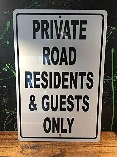 Private road sign with 'Residents & Guests Only' text on white background with black letters, mounted on a wooden surface.