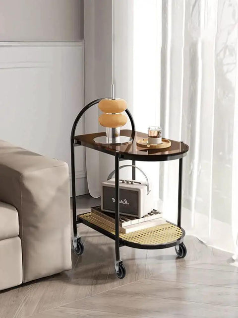 Decorative side table with lamp and books on wheels beside a sofa and window