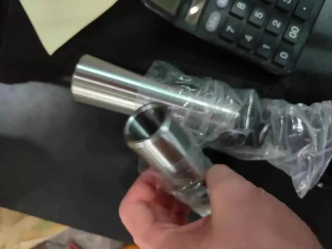 Close-up of a silver steel Morse taper reducing adapter sleeve held by hand; for lathes and drill presses