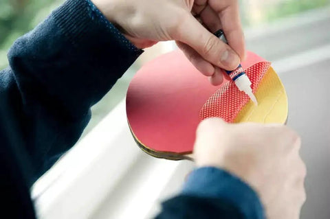 Person using Clear Quick Dry Super Glue For Plastic Wood Metal 2 Pack Precise Piercing Tube to attach rubber to table tennis paddle